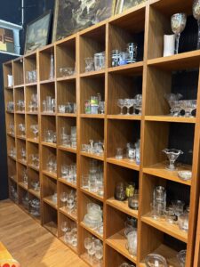 Hyllesystem med glass, kopper og serviser organisert i Second Chance–butikken