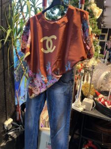 Klær med farger og detaljer, inkludert merkeplagg, i bruktbutikken