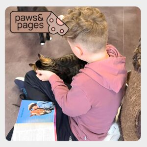 Child reading aloud while a cat listens calmly