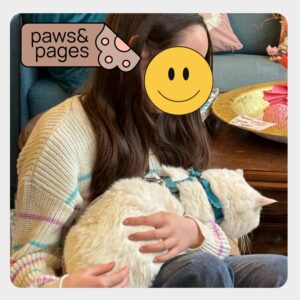 Child sitting next to a resting cat during Paws & Pages