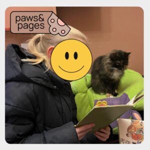 Child reading aloud with a cat present during Paws & Pages